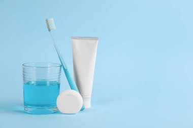 Açık mavi arkaplanda gargara, diş fırçası, macun ve diş ipi, metin için boşluk