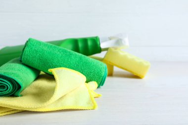 Mikrofiber bezler, süngerler ve deterjan beyaz masada, yakın plan. Metin için boşluk