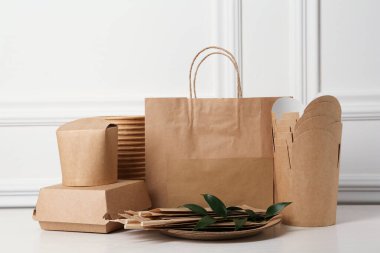 Tek kullanımlık çevre dostu ürünler beyaz ahşap masada.