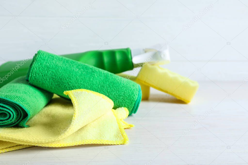 Microfiber cloths, sponges and detergent on white table, closeup. Space for text
