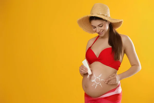 黄色の背景に太陽の保護クリームを持つ若い妊婦 テキストのためのスペース — ストック写真