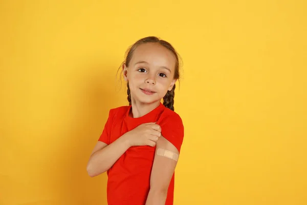 Vaccinated Little Girl Showing Medical Plaster Her Arm Yellow Background — Stock fotografie