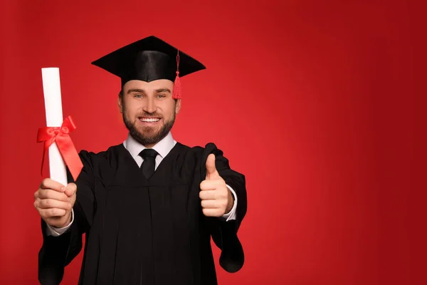赤い背景に卒業帽子と卒業証書を持つ幸せな学生 テキストのスペース — ストック写真