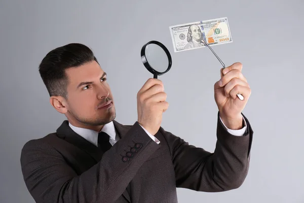 Expert Authenticating 100 Dollar Banknote Magnifying Glass Light Grey Background — Stock Photo, Image