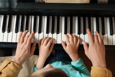 Piyano çalan çocuklu genç bir kadın. Müzik dersi