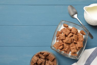 Açık mavi ahşap masada servis edilen sütlü mısır gevreği. Metin için boşluk