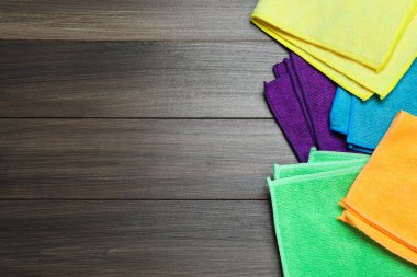 Ahşap masanın üzerinde bir sürü renkli mikrofiber kumaş var. Metin için boşluk