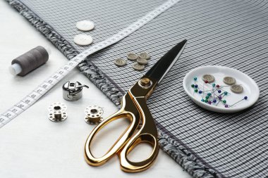 Beyaz ahşap masa üzerinde farklı dikiş malzemesi ve kumaş bileşimi.