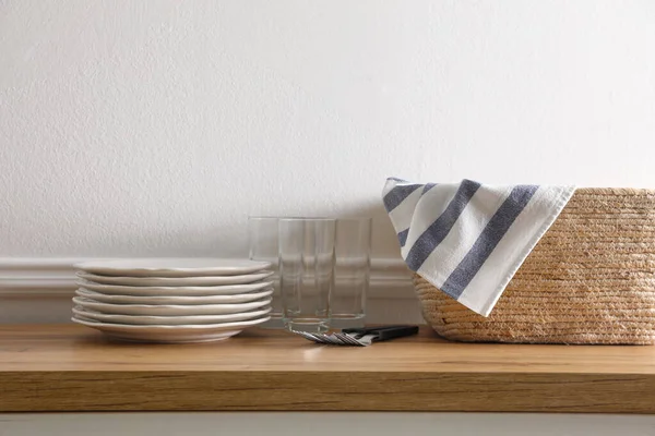 Küchentuch Weidenkorb Und Sauberes Geschirr Auf Holztisch Neben Weißer Wand — Stockfoto