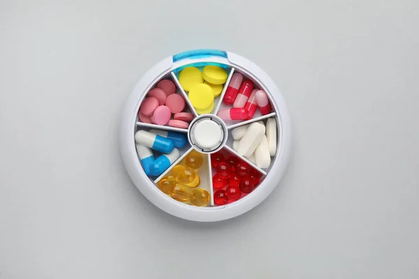 ライトグレーの背景に異なる薬とプラスチック製の箱 トップビュー — ストック写真