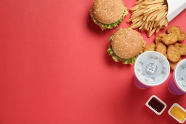 Kırmızı arka planda lezzetli fast food menüsü olan düz kompozisyon. Metin için boşluk