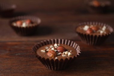 Delicious chocolate candies with hazelnuts on wooden table, closeup clipart