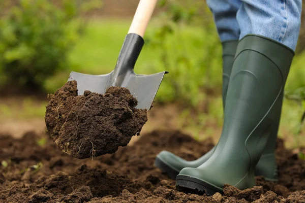 Worker digging soil with shovel outdoors, closeup. Gardening tool