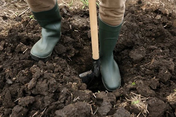 Worker digging soil with shovel outdoors, closeup