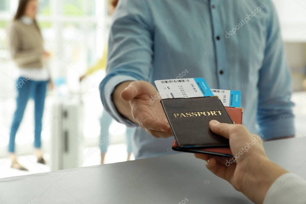 Agent giving passports and tickets to man at check-in desk in airport, closeup
