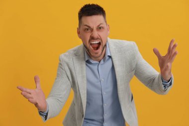 Angry man yelling on yellow background. Hate concept