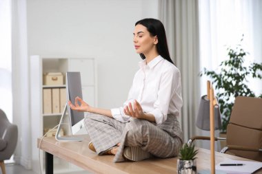 Genç bir kadın işyerinde meditasyon yapıyor. Stres atma egzersizi.