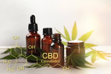 Kenevir yaprağı, krema, CBD yağı ve beyaz ahşap masa üzerindeki THC tentürü.