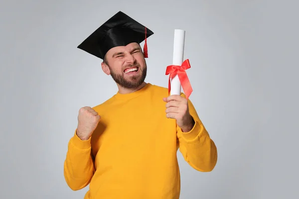Emotionele Student Met Afstudeerhoed Diploma Lichtgrijze Achtergrond — Stockfoto