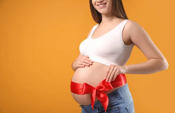 Young Pregnant Woman Red Bow Her Belly Yellow Background Closeup — ストック写真