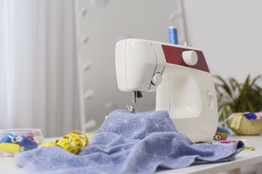 Modern dikiş makinesi, kumaş ve aksesuarlar masa içinde.