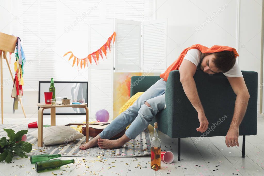 Young man sleeping on sofa in messy room after party