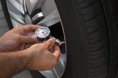 Man checking air pressure in car tire, closeup