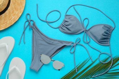 Açık mavi arka planda şık bikini ve plaj aksesuarları, düz yatış