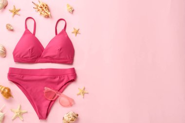 Pembe arka planda şık bikini ve plaj aksesuarları, düz yatış. Metin için boşluk