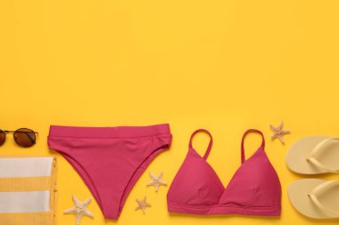 Sarı arka planda şık bikini ve plaj aksesuarları, düz yatış. Metin için boşluk