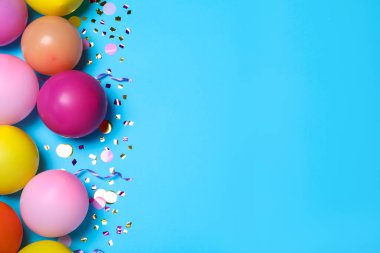 Açık mavi arkaplanda bir sürü balon ve konfeti vardı. Dümdüz uzanıyordu. Doğum günü dekoru