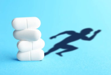 Doping konsepti. Turkuaz arka planda beyaz haplar ve sporcunun silueti