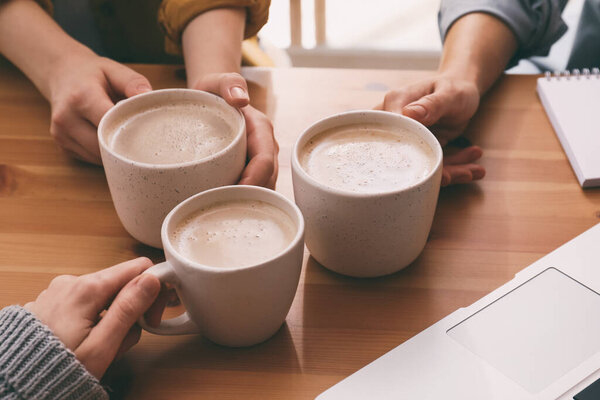 Женщины с чашками кофе за столом в кафе, крупным планом