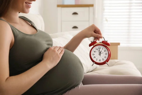 自宅近くで目覚まし時計を持っている若い妊婦は クローズアップ 出産までの時間 — ストック写真