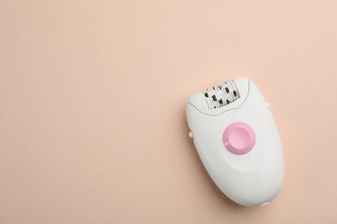 Bej arka planda modern epilatör, üst görünüm. Metin için boşluk