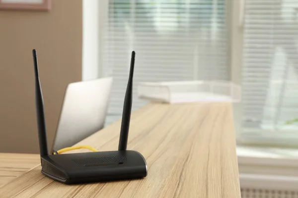 Modern wi-fi router on wooden counter indoors