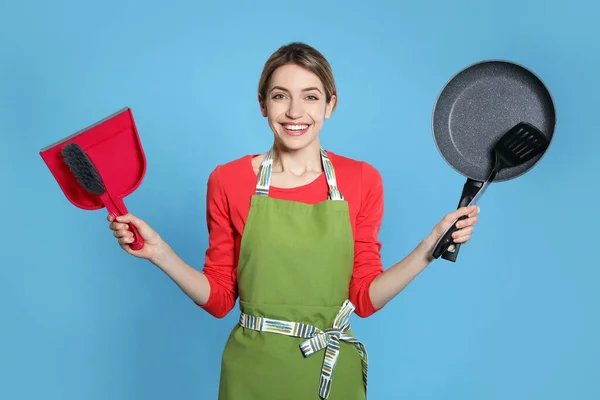 Jonge Huisvrouw Met Stofblik Borstel Koekenpan Spatel Lichtblauwe Achtergrond — Stockfoto