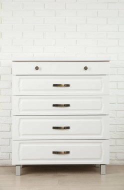 Beyaz tuğla duvarın yanındaki modern çekmeceler.