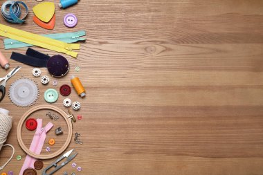 Ahşap arka planda farklı dikiş aksesuarları olan düz bir kompozisyon. Metin için boşluk