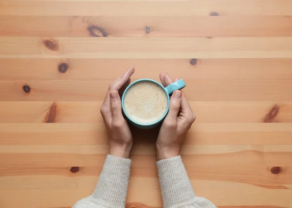 木製のテーブルでコーヒーのカップを持つ女性 トップビュー — ストック写真