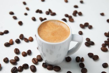 Lezzetli bir espresso ve kahve çekirdekleri beyaz masada.
