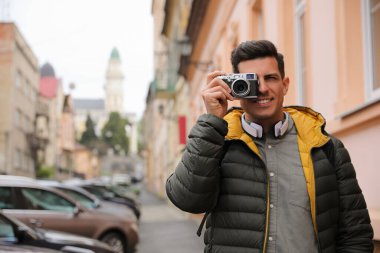 Şehir sokaklarında fotoğraf çeken kameralı bir turist.