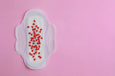 Menstrual ped ve pembe arka planda konfeti, üst manzara. Metin için boşluk