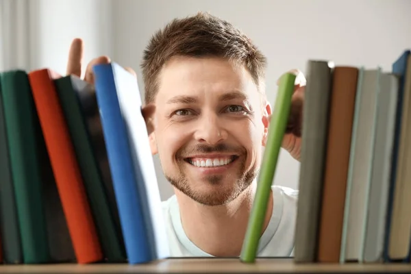 Man searching for book on shelf in library
