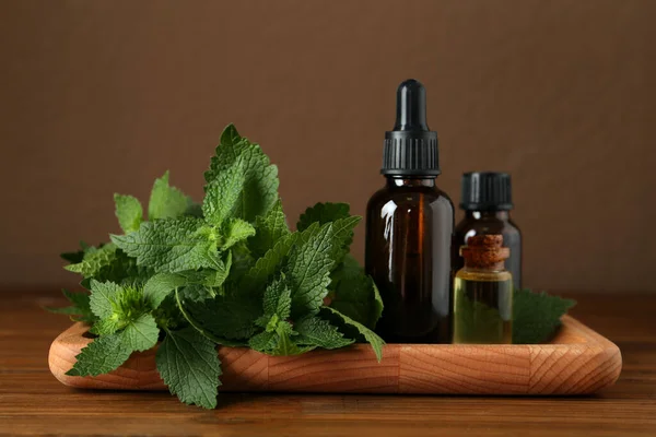 Bandeja Con Botellas Aceite Ortiga Hojas Frescas Sobre Mesa Madera — Foto de Stock