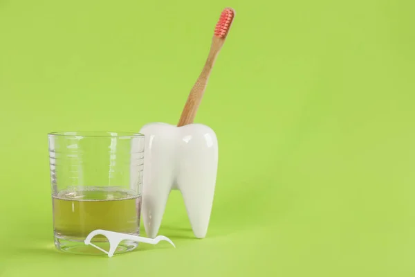 Mouthwash, toothbrush, holder and dental floss pick on light green background, space for text