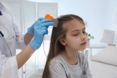 Klinikte kızın saçında bit tarağı kullanan bir doktor. Bit önleyici tedavi