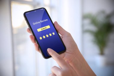 Akıllı telefonu kapalı alanda geri bildirim yapmak için kullanan bir kadın, yakın çekim. Müşteri değerlendirmesi