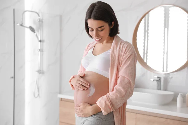 Jovem Grávida Aplicando Produto Cosmético Barriga Banheiro — Fotografia de Stock