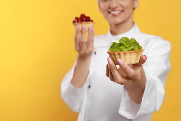 Felice Pasticcere Professionista Uniforme Con Deliziose Tortine Sfondo Giallo Primo — Foto Stock